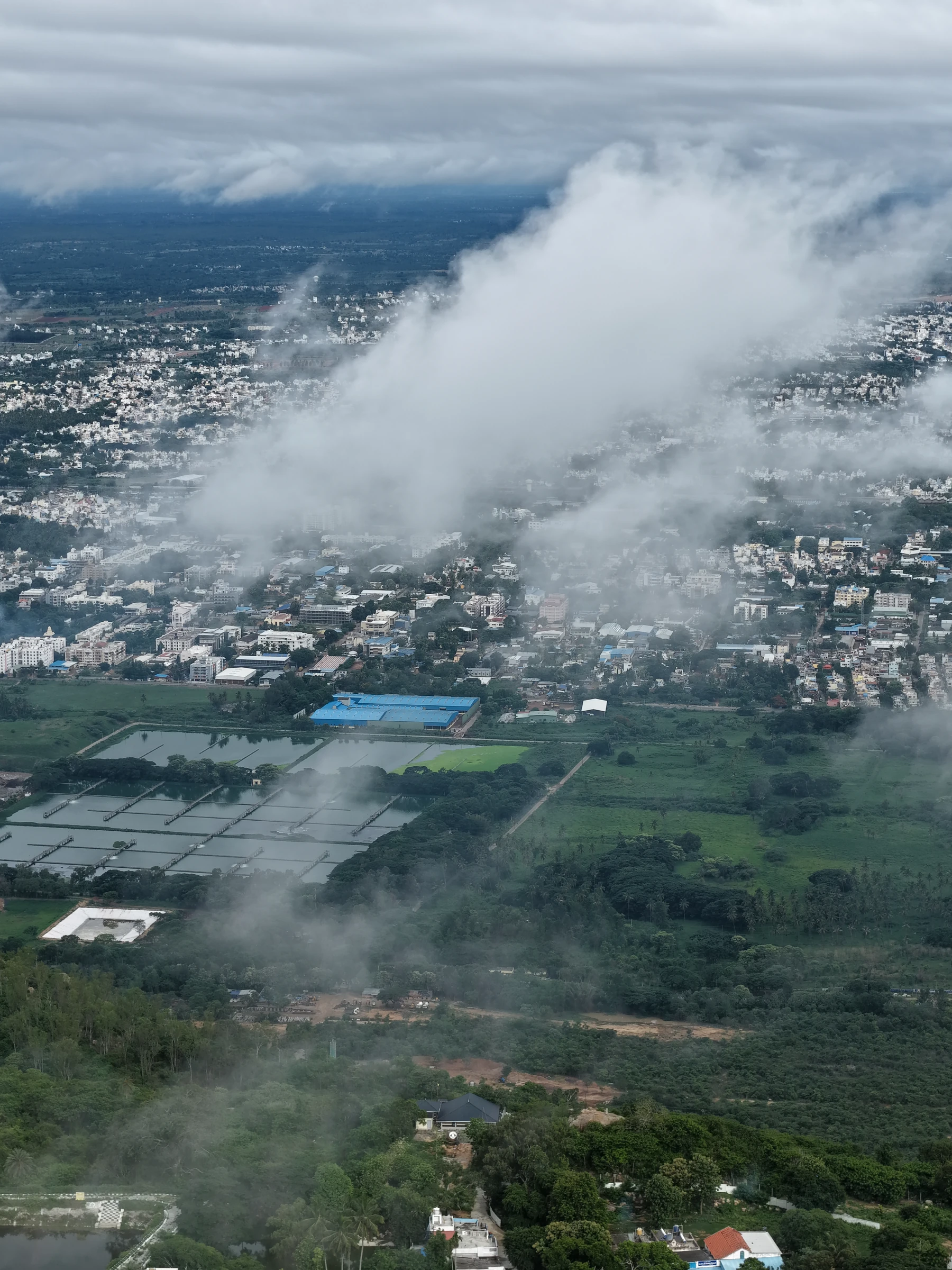 Clouds above a city and surrounding green landscape, photographed by Mamathesh Gowda