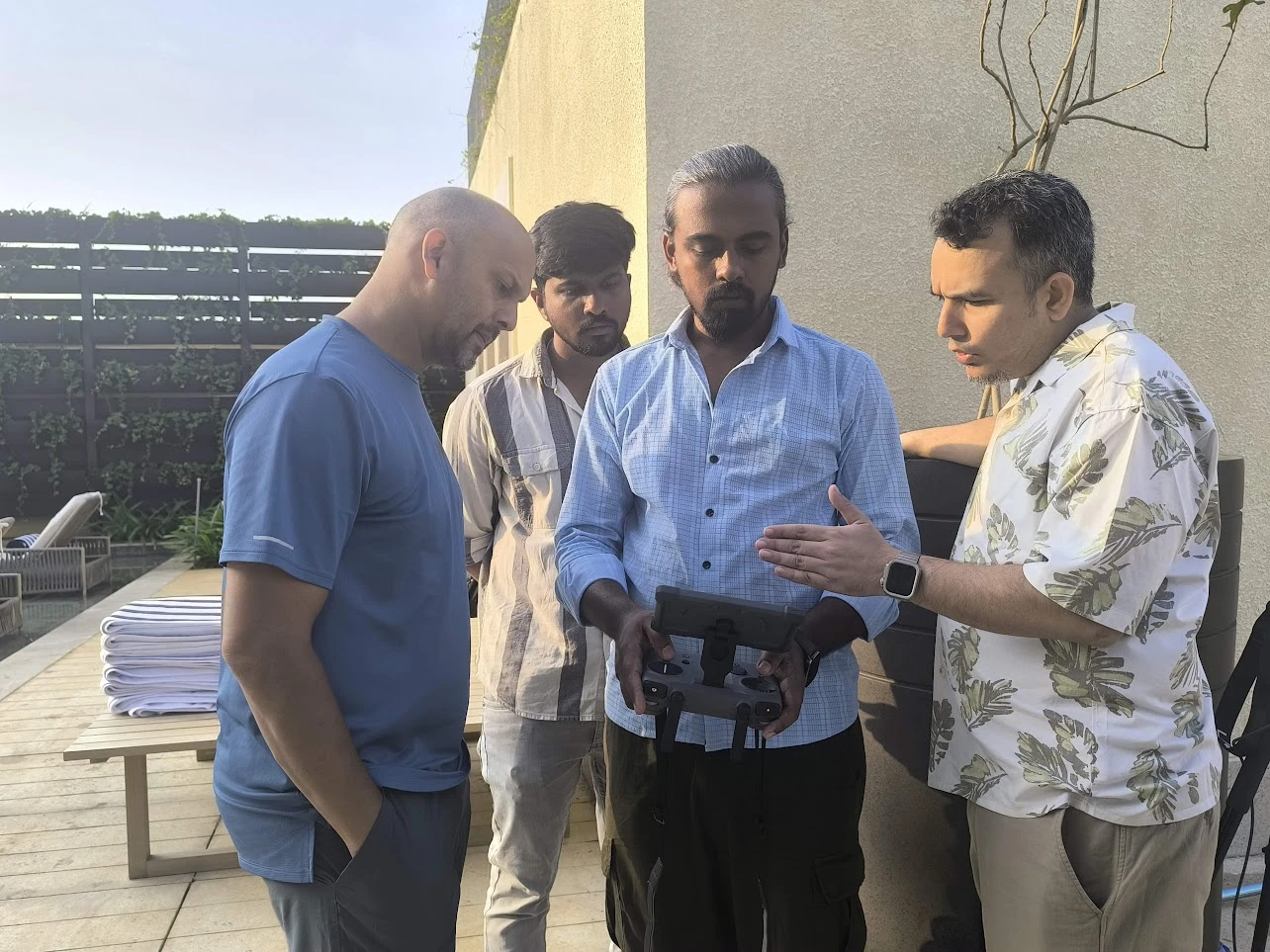 Mamathesh holding a drone controller while discussing the shoot with people on location